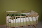 Crib decked out with quilt, lamb skin and sheep